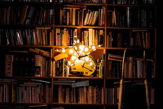A bookshelf illuminated by a star-shaped lamp.