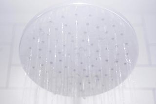 A showerhead spraying water from above. Steam is obscuring part of the showerhead.