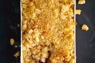 Overhead shot of a casserole dish full of baked macaroni, crispy breadcrumbs on top.