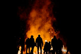 Photo of people standing around a fire by Alessio Soggetti on Unsplash