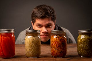 Man staring at 4 jars of homegrown canned food as part of the canning comeback.