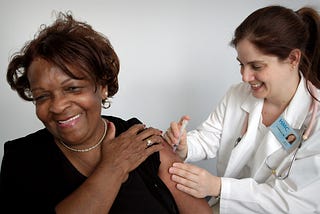 A healthcare professional administers a vaccine dose to a female patient.