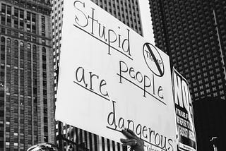 A protest holding a placard that reads: Stupid people are dangerous.