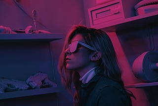 Fururistic cyberpunk style image in a pink tone of a woman with sunglasses in a room, kneeling and looking up.