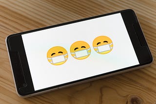 Emoticons with face masks on a phone screen.
