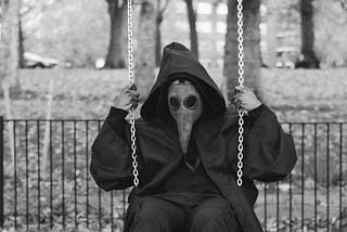 Man in odd bird mask on swing set