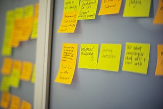 A variety of yellow post-its are stuck onto a board.