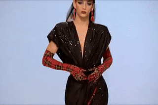 GIF: Drag queen Violet Chachki on RuPaul’s Drag Race walking a runway and revealing a red garment from under a black one