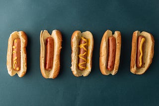 Five hot dogs against a blue background