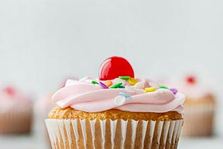 A cupcake with icing and a cherry on top