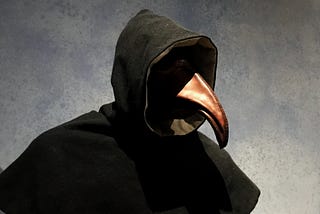 A person with a hood and a mask of a plague doctor