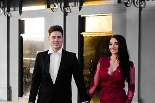 A beautiful couple leaving a hotel, holding hands.