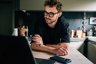a man with glasses leaning across a kitchen island