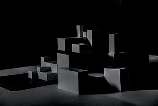 A dark photo of several boxes of different shapes and sizes.