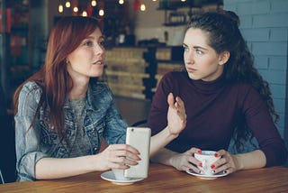 Two women sitting next to each other in a cafe