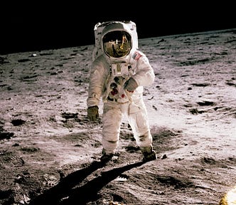 A man in an astronaut suit standing on the Moon. Soil is grey.