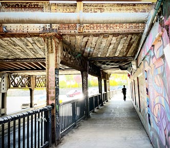 Person walking under rail bridge in Toronto’s Junction neighbourhood.