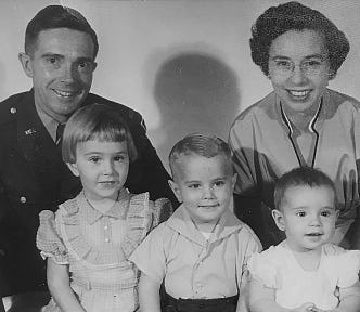 Photograph of the author’s family when he was two years old, with him and his sisters sitting in front of their smiling parents.