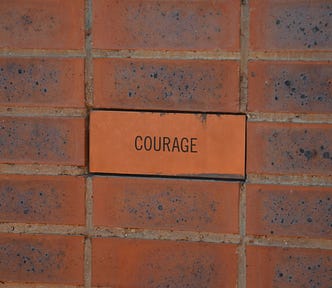 The word courage written on a brick wall.