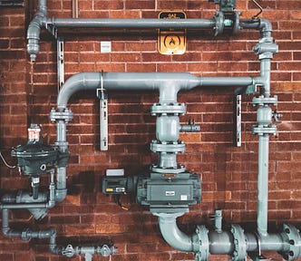 pipelines connected at different stages in front of a brick wall.