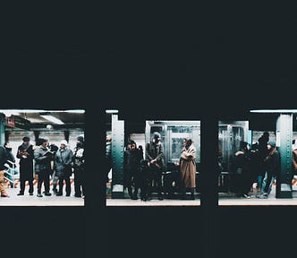 A group of people stand in a subway awaiting a train