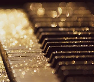 Gold dazzling specs sprinkled over piano keys in early morning light.