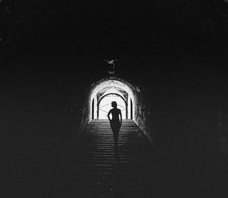 A figure in a dark tunnel