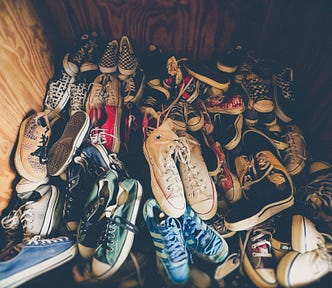 A wooden cubby filled with dozens of disordered shoes, each varying in color, shape, and position.