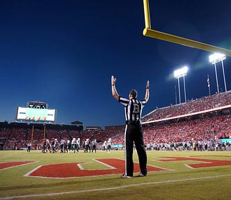 Football referee holding his hands up indicating a successful field goal