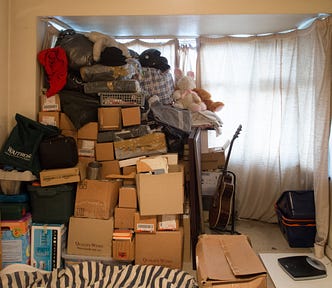 A room in a house cluttered with a pile of cardboard boxes