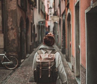 Person wearing a backpack walking in an alley