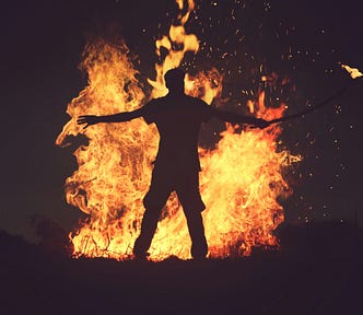 Man standing in front of a bonfire at night.