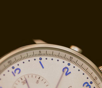 A beautiful watch face, white with blue numbers occupies the lower half of the image. The long hand is at the 2 mark.