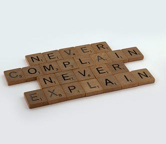 Letters that read ‘Never complain, never explain’.