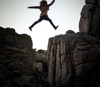 person leaping between two rocks
