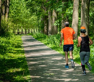 Two mature individual jogging in the park.