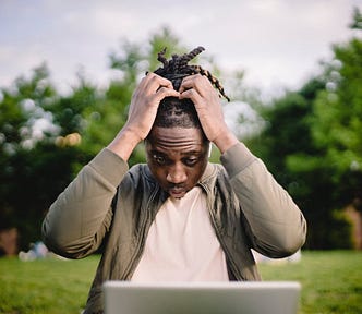 stressed black man entrepreneur on a laptop in the park