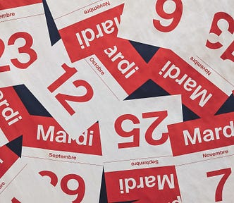 Pages of a tear-off calendar lie scattered on a black background. The pages display the month in bold and the date below in a heavy font.