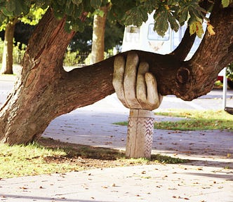 Image of a large hand holding up a tree.