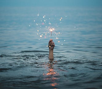 Person holding firecracker while submerged in water