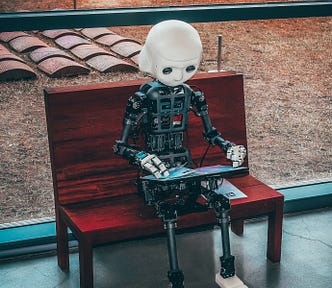 Robot on bench with laptop computer