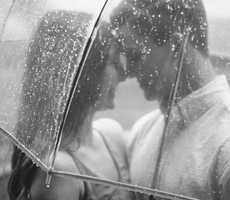 Couple in love standing in the rain under an umbrella.