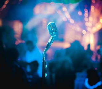 An unmanned microphone on stage, bright lights in the background