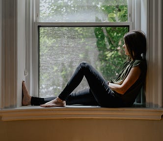 A home bound woman looks out a window. She suffers from much affliction yet endures by nature sightings tapping on her pane.