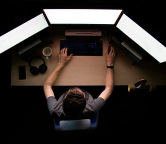 Man working on three monitors
