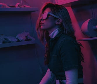 Fururistic cyberpunk style image in a pink tone of a woman with sunglasses in a room, kneeling and looking up.