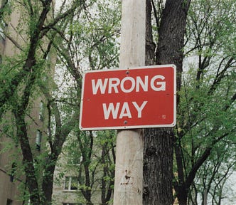 A red sign on the street that says “wrong way”