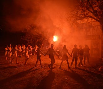 a group of revelers in a circle, hands joined, orange color palette