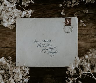 Old letter surrounded by dried white hydrangeas