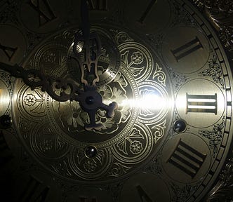 Photo of a brass clock face with a horizontal stream of light across it.